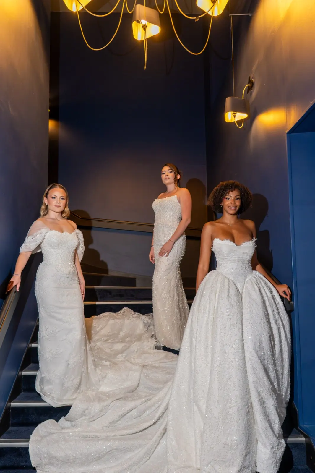 Trois mariées en robe Dacosta Couture dans un escalier